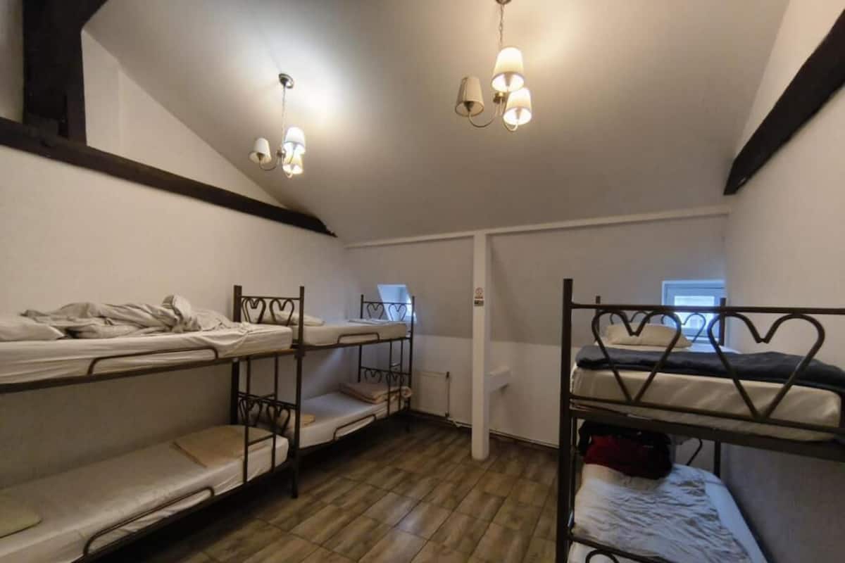 Um quarto de dormitório com beliches, piso de madeira e porta branca.