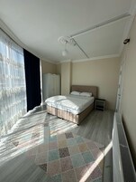 Un dormitorio con cama, armario, radiador y ventana con cortinas.