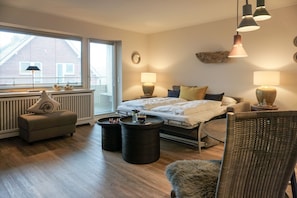 Ein modernes Schlafzimmer mit Bett, Nachttischlampen, Heizkörper, Fenster und Blick auf ein Gebäude.