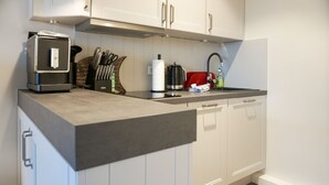 Una cocina moderna con armarios blancos, encimera negra y electrodomésticos de acero inoxidable.