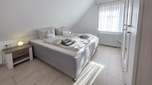 Een moderne slaapkamer met een bed, nachtkastje en een raam met gordijnen.