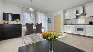 Eine moderne Küche mit weißen Schränken, einem Einbauofen und einem Essbereich mit einem schwarzen Tisch und Stühlen.