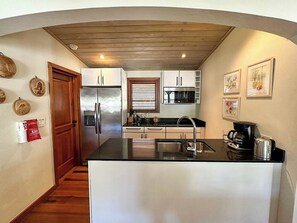Una cocina compacta con una isla central, electrodomésticos de acero inoxidable y armarios de madera.