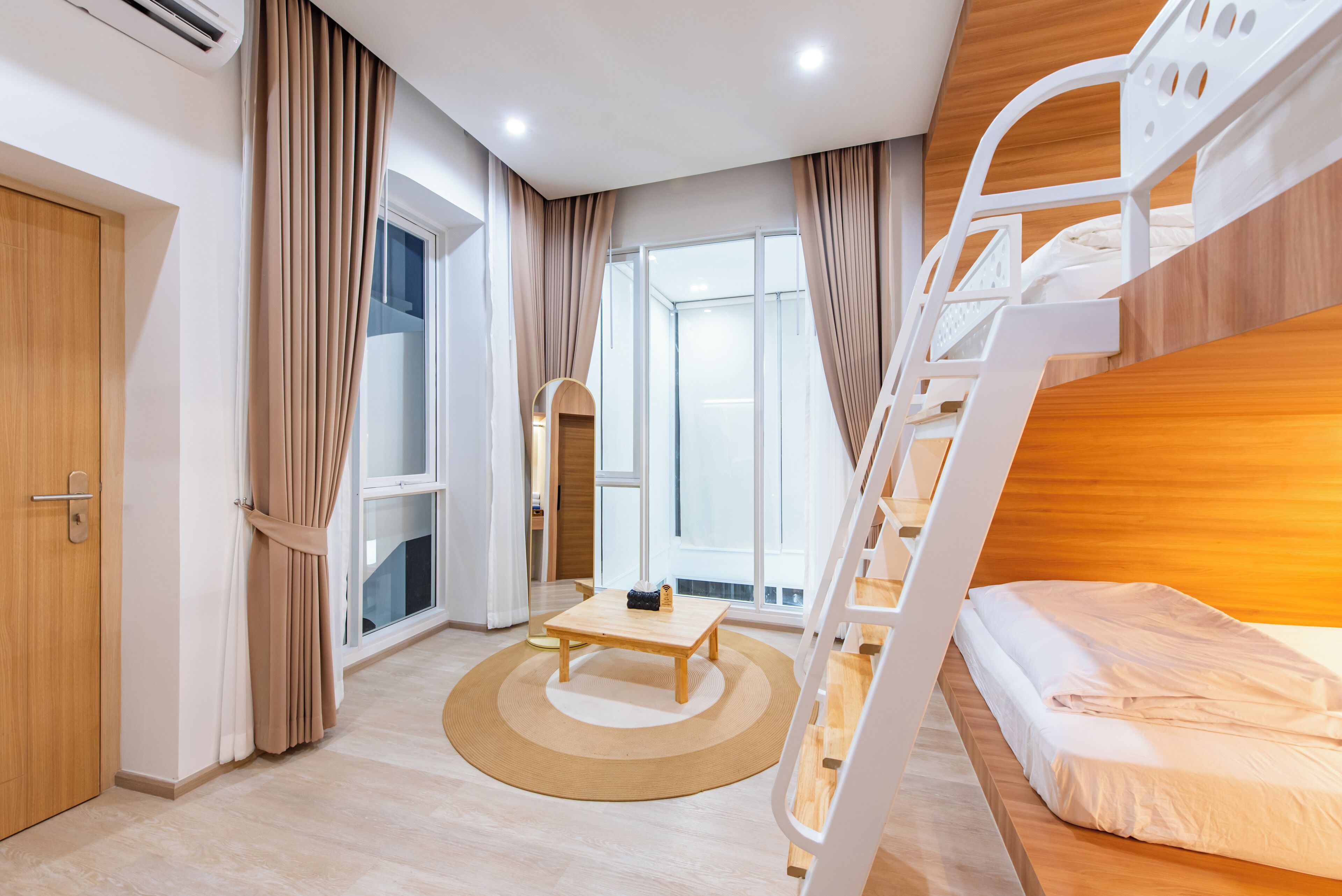 A modern room with a bunk bed, a wooden desk, and a large window.