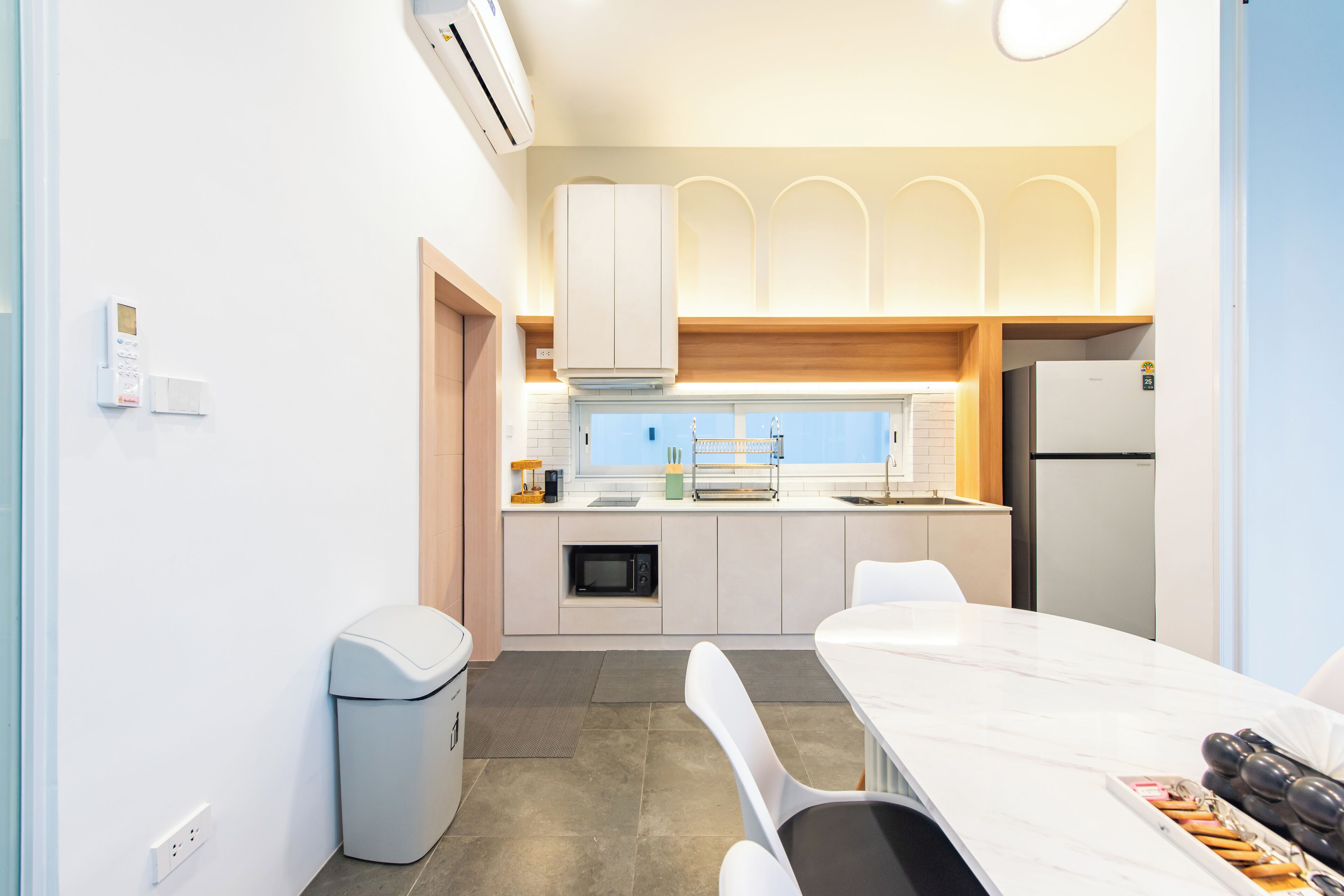 A modern kitchen with white cabinets, a built-in microwave, and a large window.