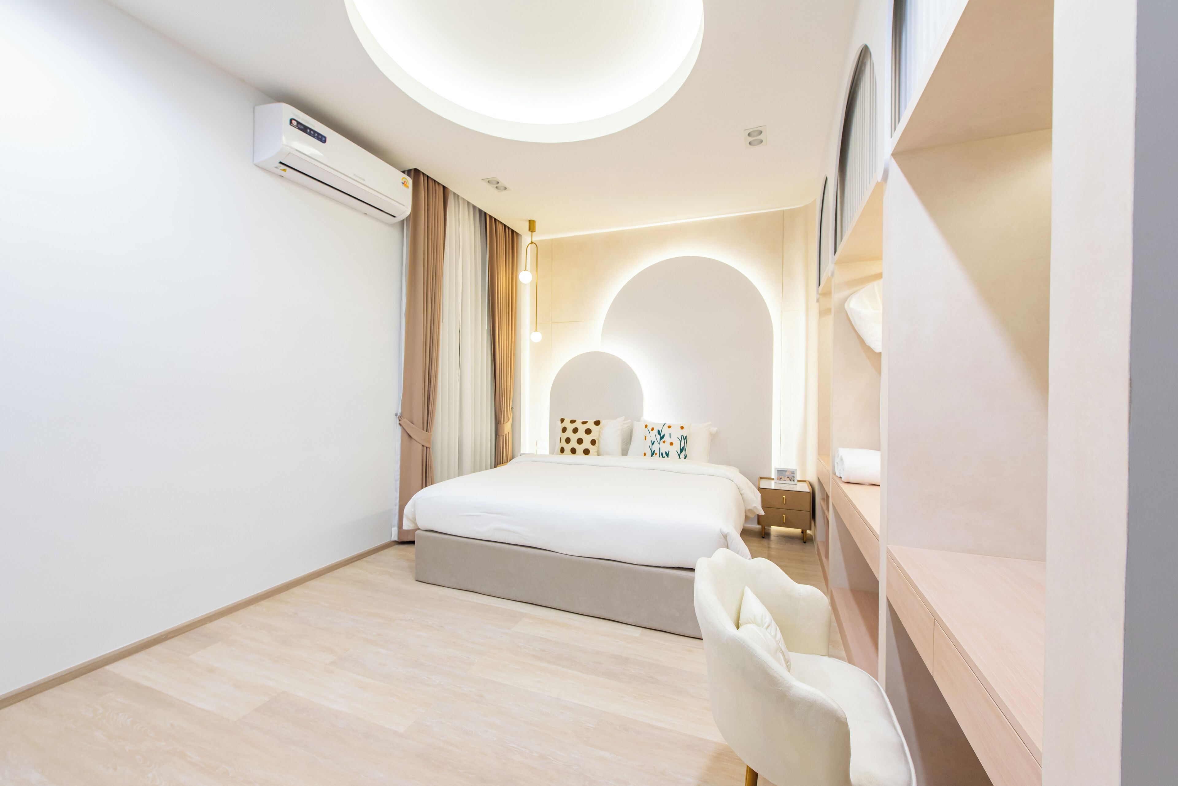 A modern hotel room with a large bed, an air conditioning unit, a desk, and a chair.