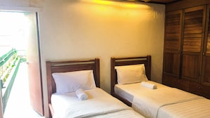 Two single beds with wooden headboards and white linens in a room with a wooden wardrobe and a balcony with a green railing. - HOTEL I VILLA INN (Kuala Lumpur)