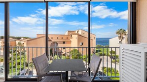 Un balcón con mesa y sillas, vista a edificios y cielo despejado.