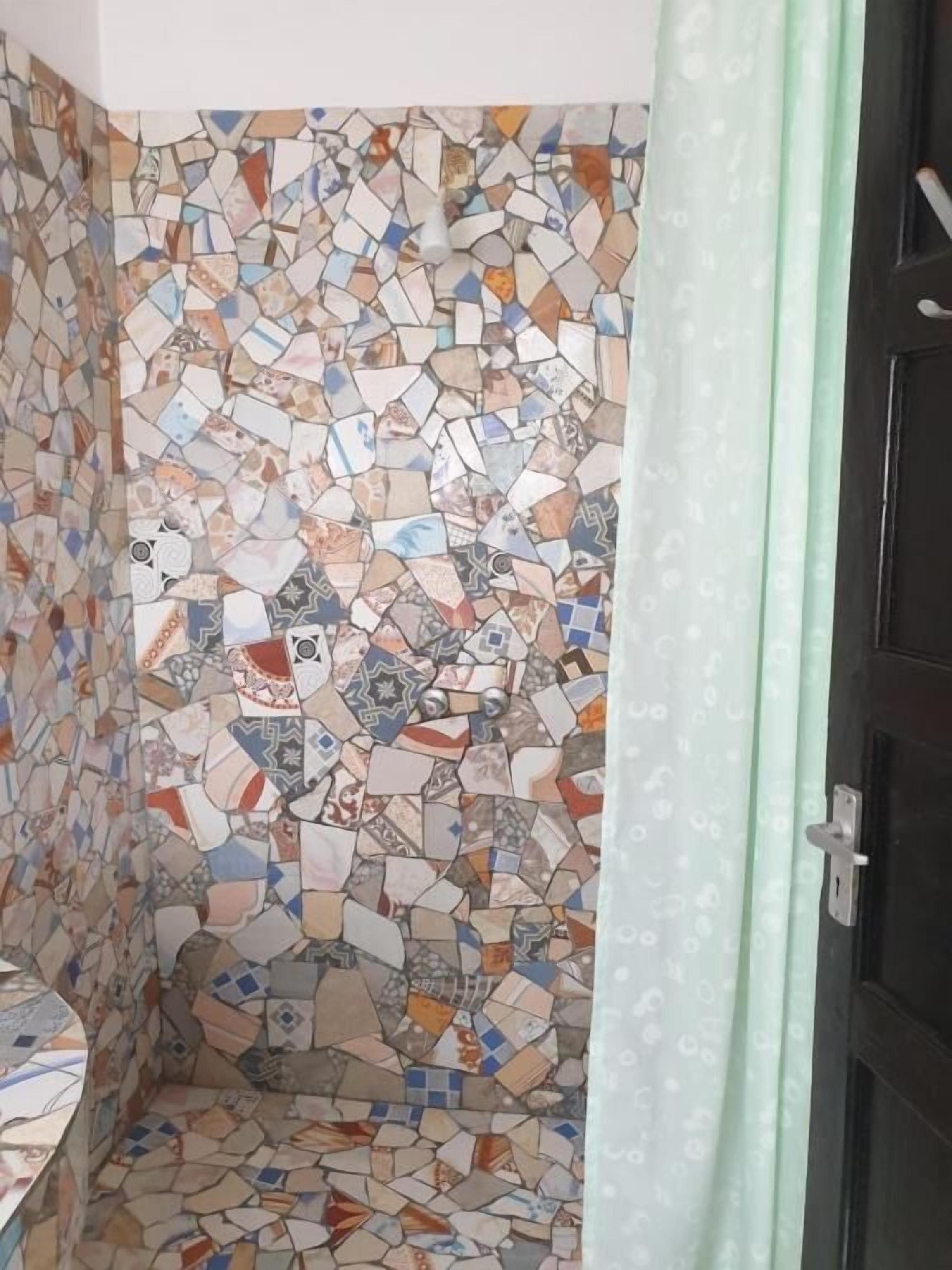 A bathroom with a mosaic tile wall and a shower curtain.