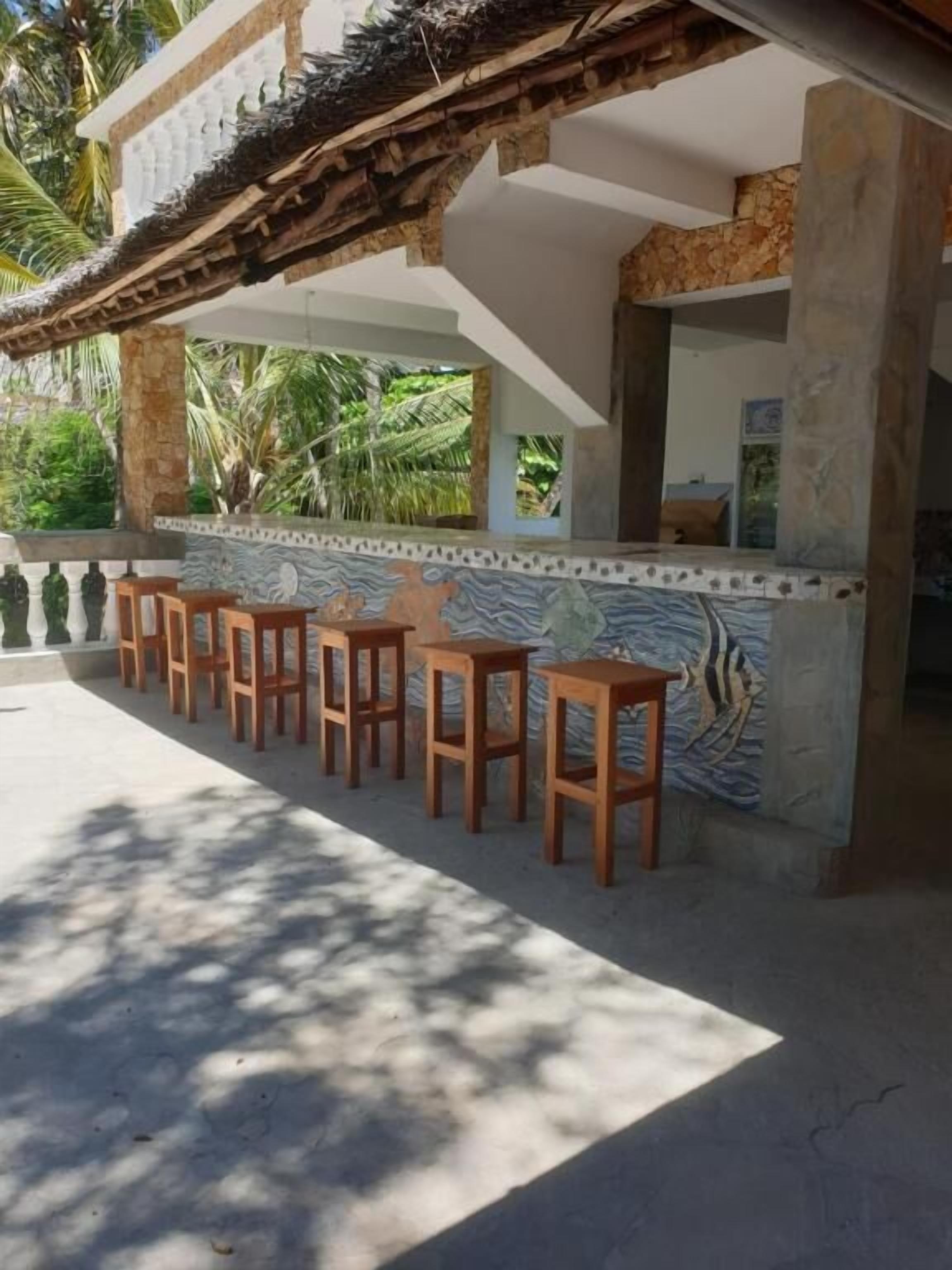Un área de bar al aire libre con taburetes de madera y un muro de azulejos.