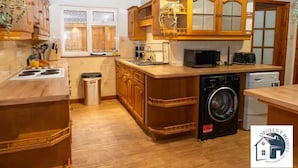 A kitchen with wooden cabinets, a stove, a microwave, a washing machine, and a dishwasher.