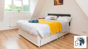 A bedroom with a bed, a window, and a painting on the wall.