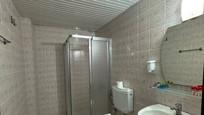 A bathroom with a shower, toilet, sink, and mirror.