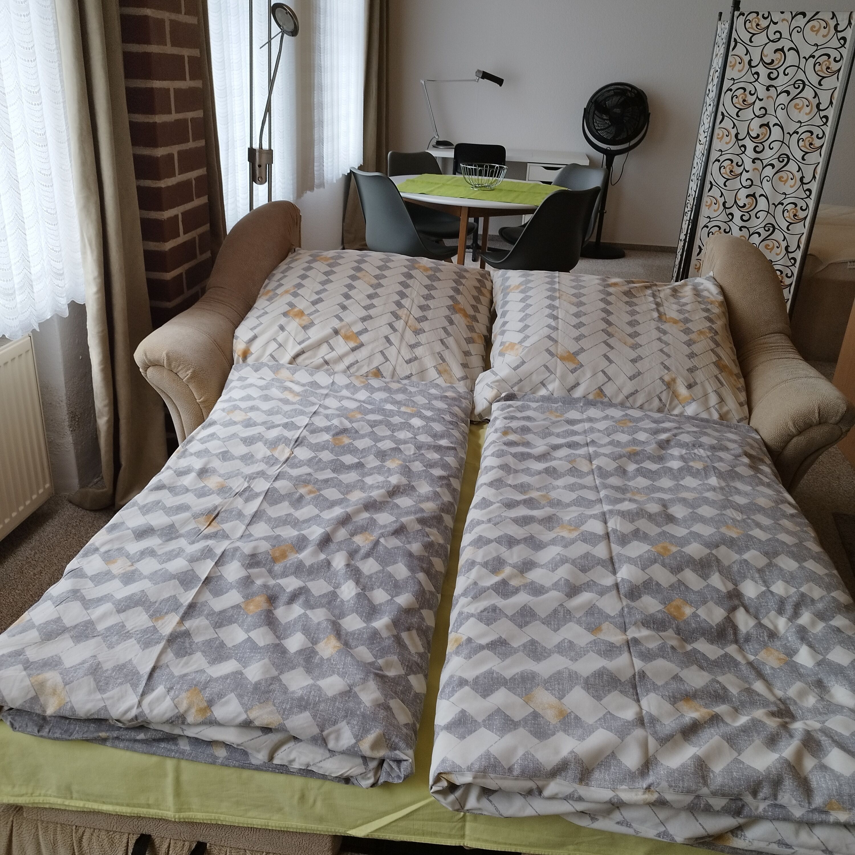 Une chambre à coucher avec un lit, deux chaises, un bureau et un radiateur.