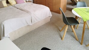 A bedroom with a bed, a wooden wardrobe, a desk with a chair, and a small table with a green tablecloth. - Beautiful bright 60 sqm apartment near Magdeburg city center and zoo, barrier-free (Magdeburg)