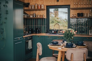 A kitchen with green cabinets, a wooden countertop, and a window with a view of greenery. - Cabin for 2 in the heart of the mountains! (J3QP+37 Măguri, Romania)