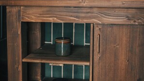 A wooden cabinet with shelves, a potted plant, and a candle.