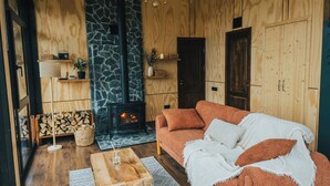 A cozy living room with a fireplace, wooden walls, a sofa, and a coffee table.