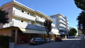 Ein mehrstöckiges Hotel mit Balkonen, einem Parkplatz und blauem Himmel.