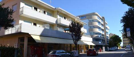A multi-story hotel with balconies, a parking area, and a clear sky.