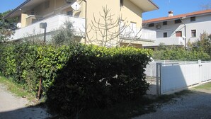 A two-story house with a balcony, a satellite dish, and a white fence. - Cozy flat with garden near beach (Grado Pineta)