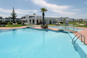 Una piscina al aire libre de temporada, sombrillas