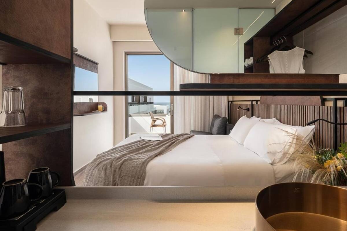 A modern hotel room with a bunk bed, a large mirror, and a view of the city.