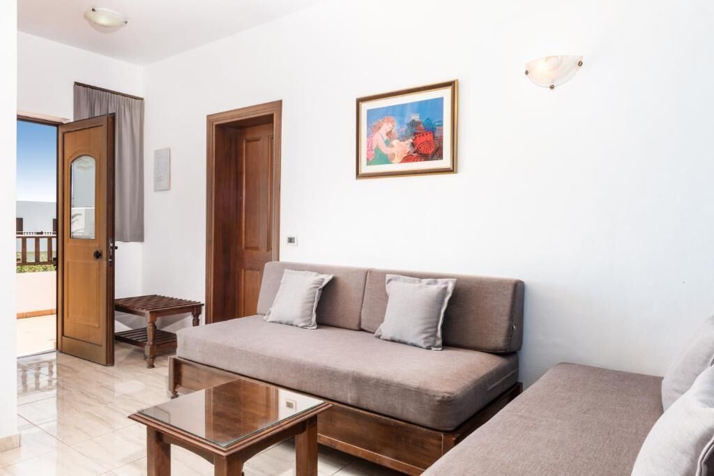 Una sala de estar con un sofá, una mesa de centro y una puerta que da a un balcón.
