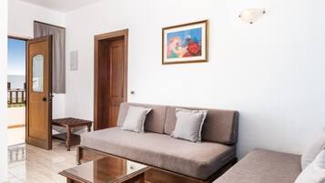 Una sala de estar con un sofá, una mesa de centro y una puerta que da a un balcón.
