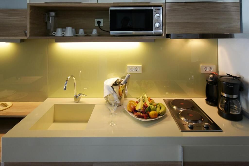 Een moderne keuken met een ingebouwde magnetron, een spoelbak, een fornuis en een koffiezetapparaat.