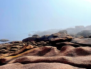 A rocky coastal landscape with large boulders and a calm sea. - Brittany Lescoat (Plestin-les-Grèves)