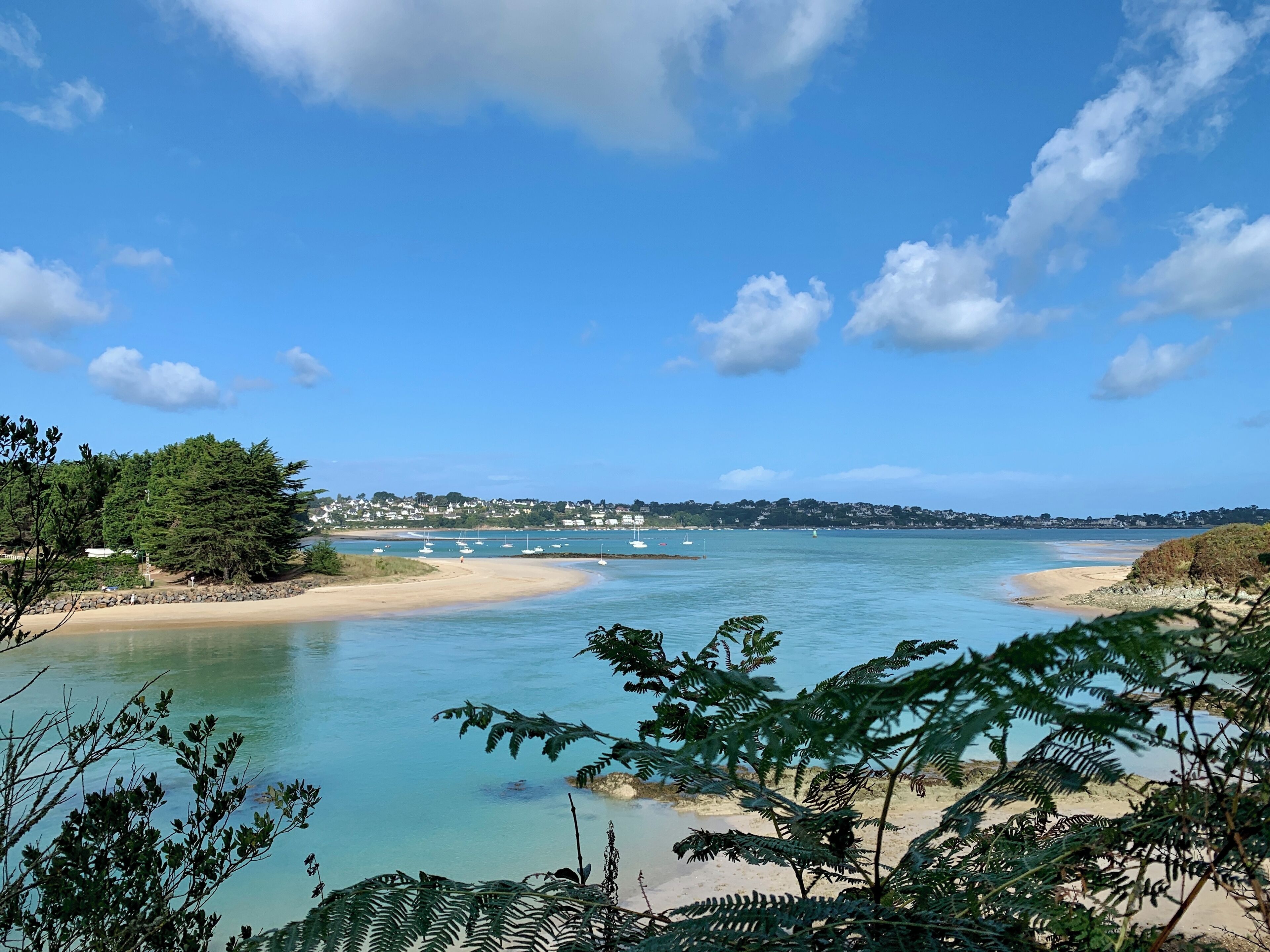 A coastal landscape with clear skies, calm waters, and a sandy beach.
