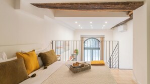 Quarto com cama, almofadas, bandeja com pastelaria, janela e escada.