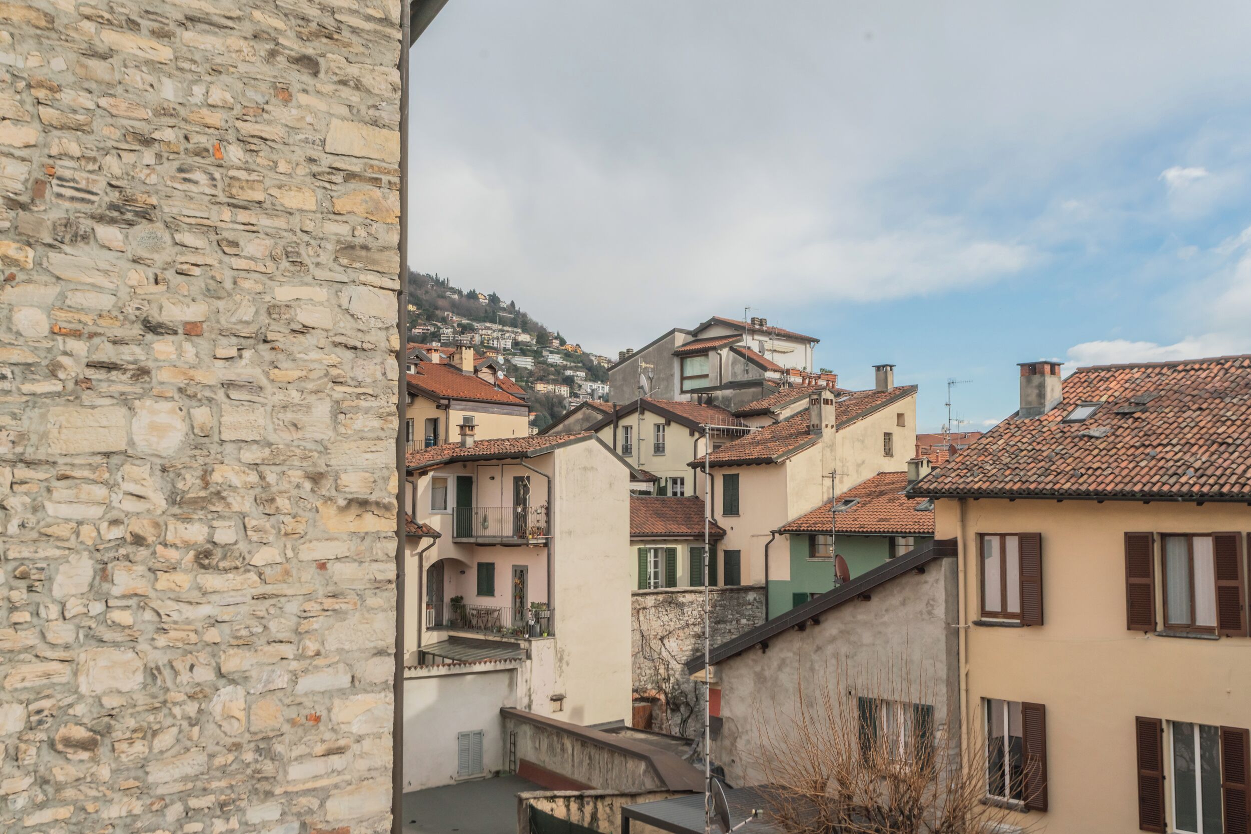 A stone wall and a view of a hillside with terraced buildings.