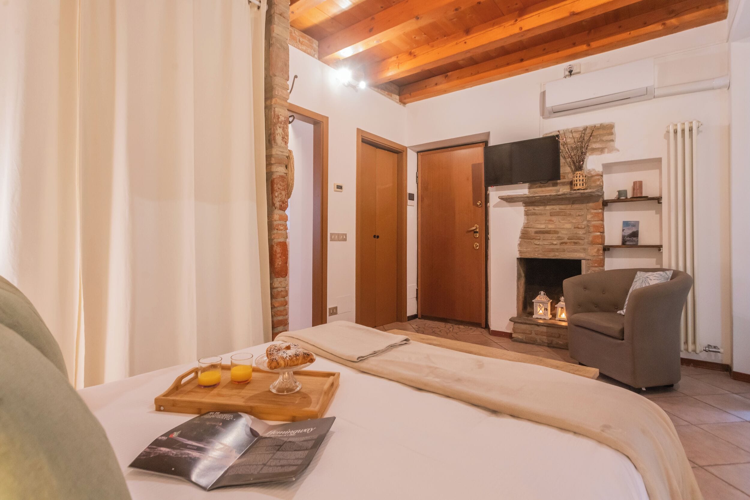 Una habitación acogedora con una cama, techo de madera, chimenea y televisión.