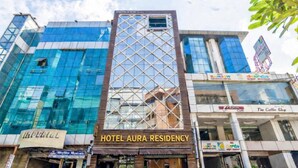 A hotel named "Hotel Aura Residency" with a modern glass facade and a distinctive geometric pattern on the upper part. - Hotel Aura Residency (Bengaluru)