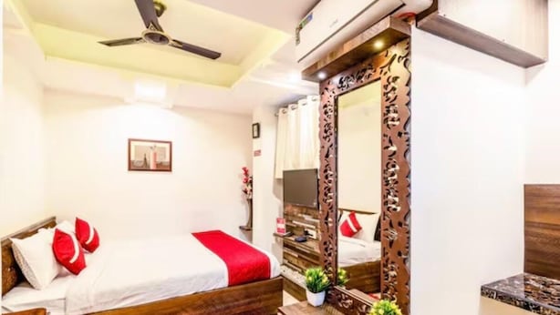 A hotel room with a bed, a mirror, a ceiling fan, and a TV. - Hotel Aura Residency (Bengaluru)