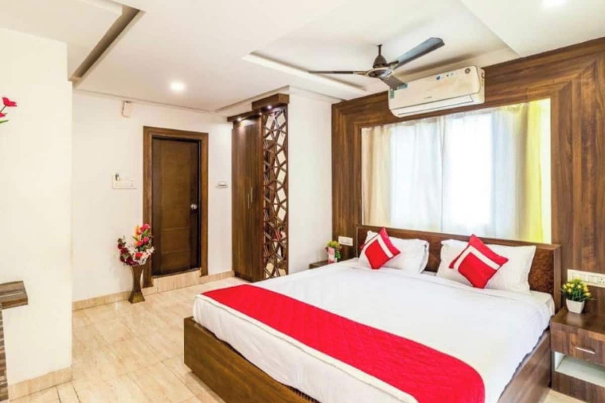 Una habitación de hotel con una cama grande, cabecero de madera y un ventilador de techo.