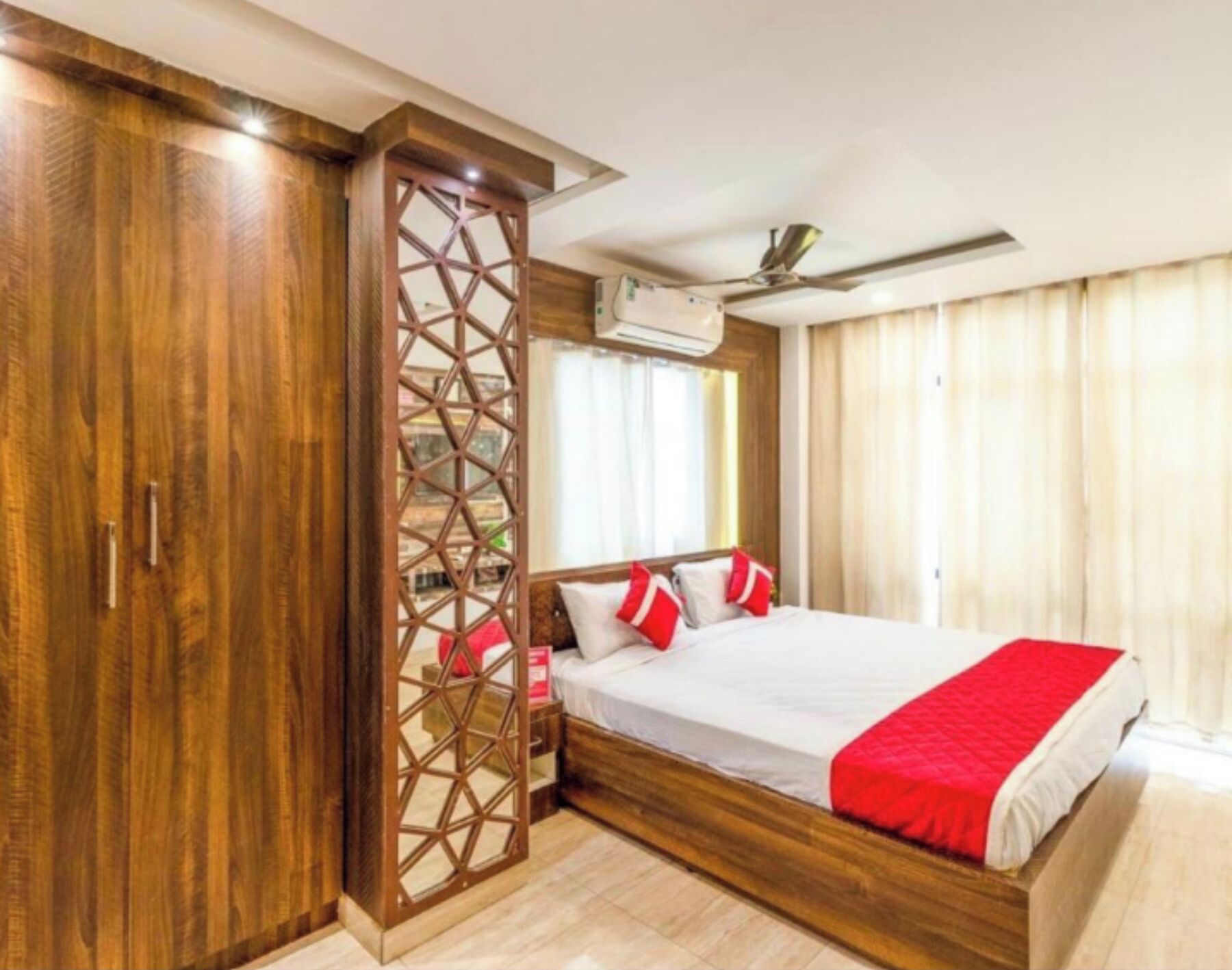Une chambre d’hôtel avec un lit en bois, une grande armoire et un ventilateur de plafond.