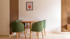Een eetruimte met een houten tafel en vier groene stoelen.