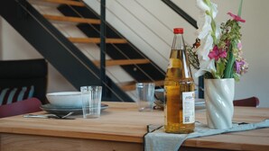 Een fles etchO op een houten tafel met een bloevas en glaasjes.