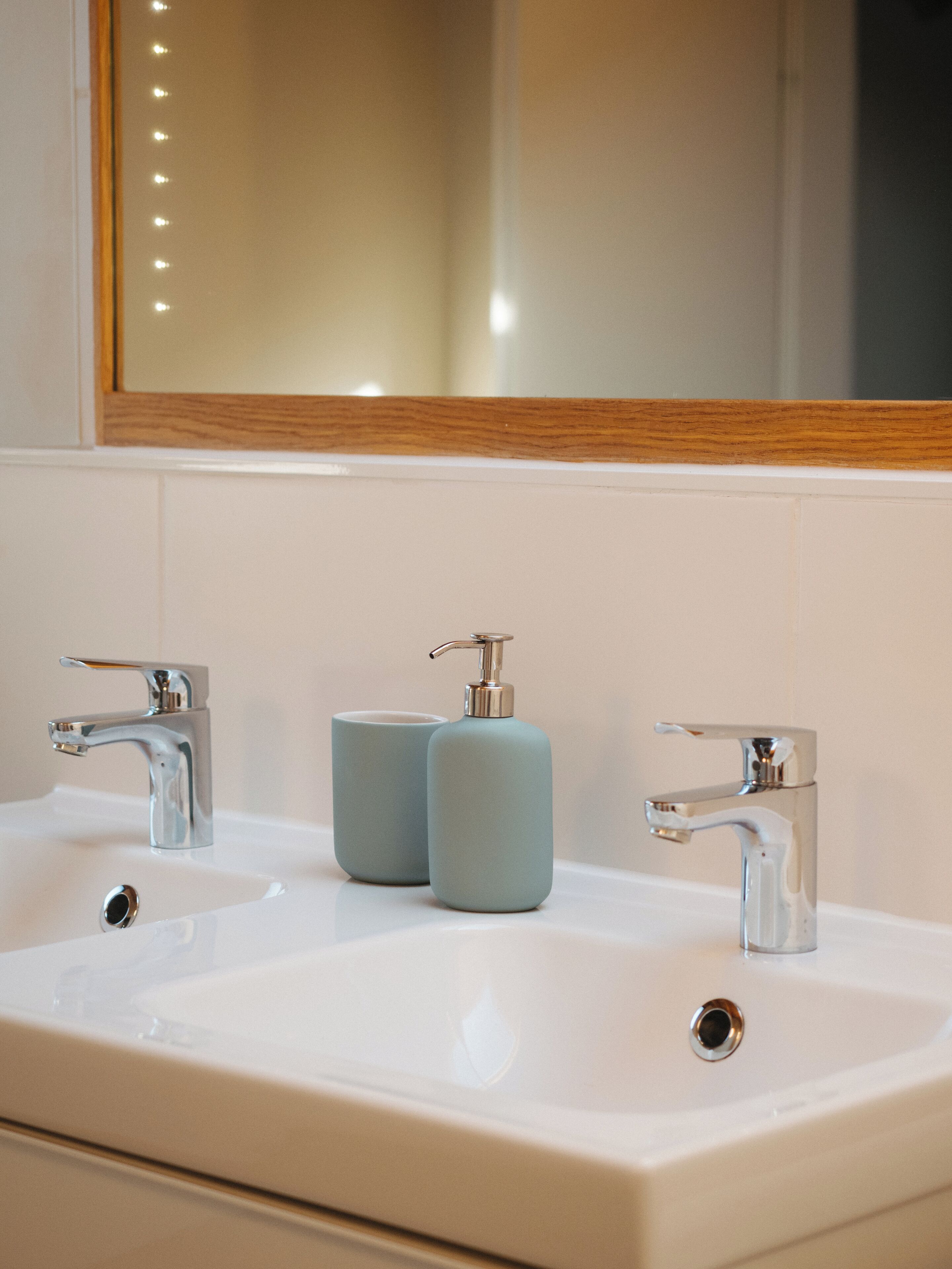 Ein Badezimmer mit zwei Waschbecken, einem Spiegel und zwei Seifenspendern.