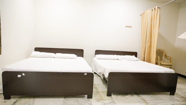 Ein Zimmer mit zwei Einzelbetten, einem Sessel und einem Vorhang.