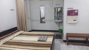 Ein Schlafzimmer mit einem Bett, einer Bank, einer Dusche, einem Waschbecken und einem Kalender an der Wand.