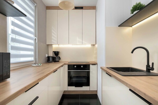 A compact kitchen with a built-in oven, a sink, and a coffee maker.