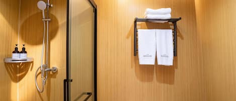 A modern bathroom with a glass shower enclosure, a toilet, and a towel rack with two towels.