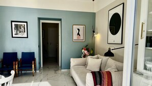 Ein Wohnzimmer mit einem weißen Sofa, blauen Sesseln, einem weißen Tisch und einem Marmorboden.