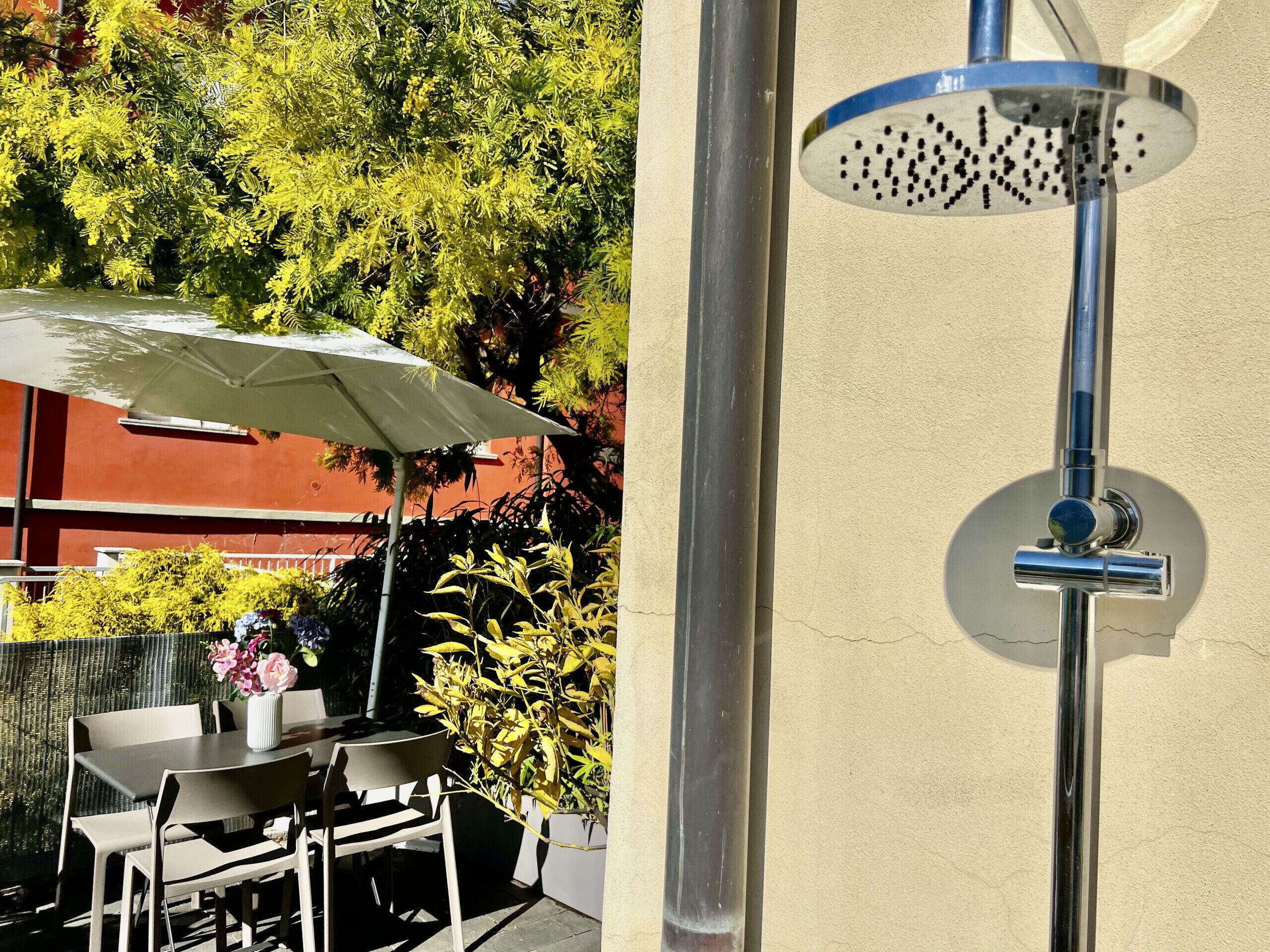 A patio area with a table and chairs, an umbrella, and a variety of plants.