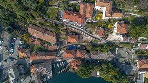 Luftaufnahme einer Küstenstadt mit terrassenförmig angelegten Häusern, einem Yachthafen und einer Straße, die zum Wasser führt.