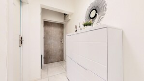 A hallway with a white door, a white cabinet, and a wall-mounted mirror with a sunburst design. - Apartment Nila by Litto (Split)